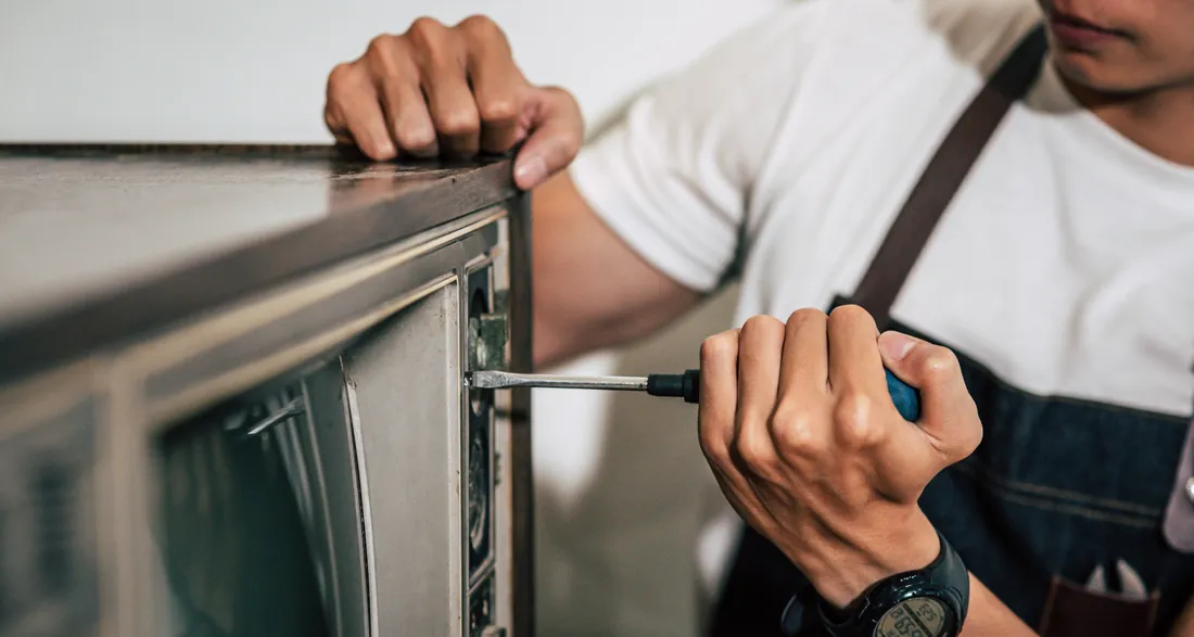Technician working on a built-in oven with a screwdriver